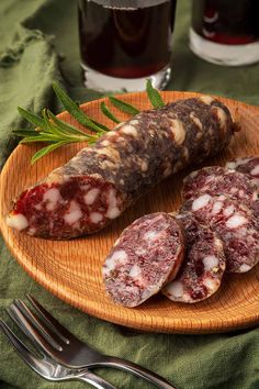 sausages on a wooden plate next to a glass of wine