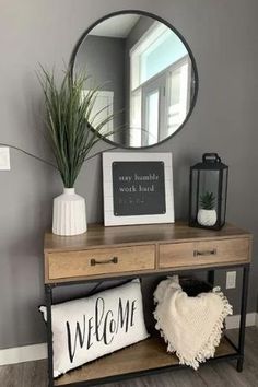 a wooden table topped with a mirror next to a plant and a sign that says welcome