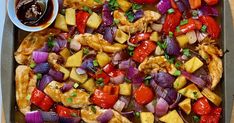 a pan filled with chicken, pineapples, onions and peppers next to a bowl of sauce