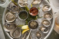 an overhead view of oysters on ice with lemon wedges and ketchup