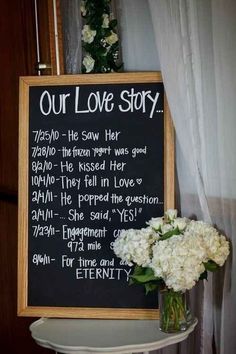 a chalkboard with the words our love story written on it next to a bouquet of flowers