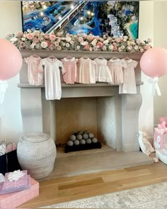 a decorated fireplace with pink balloons and baby's breath gowns on the mantle