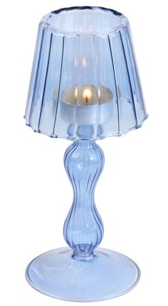 a blue glass table lamp with a lit candle in the middle on a white background