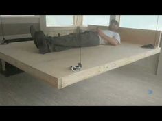 a man laying on top of a wooden table next to a pair of black shoes