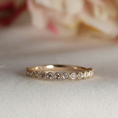 a wedding band with five diamonds on it sitting on a white cloth next to flowers