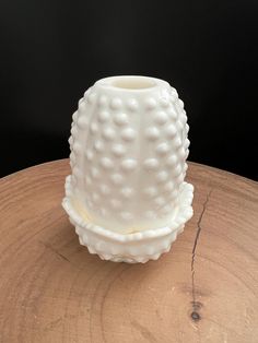 a white vase sitting on top of a wooden table