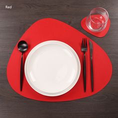 a red place mat with white plates and black utensils