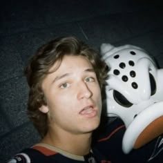 a young man holding a white mask in front of his face