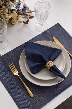 a place setting with blue napkins and gold forks