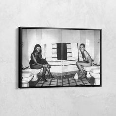 a black and white photo of two people sitting on toilets