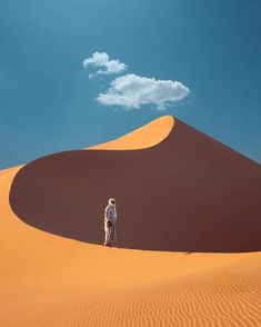 a person standing in the middle of a desert with a cloud in the sky above