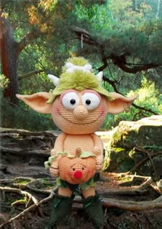 a crocheted troll doll sitting in the woods