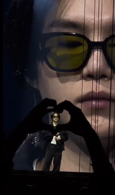 a woman in glasses making a heart shape with her hands