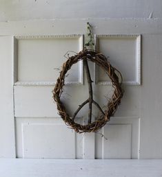 a peace sign made out of twigs hangs on a door handle in front of a white paneled door