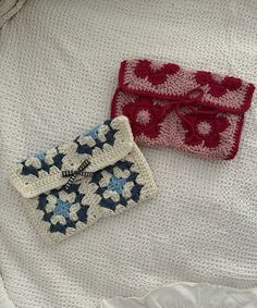 two crocheted purses sitting on top of a white cloth covered bed next to each other