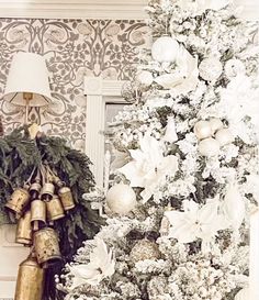 a white christmas tree with gold bells and ornaments