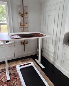 a room with a desk, phone and laptop on the floor in front of a window