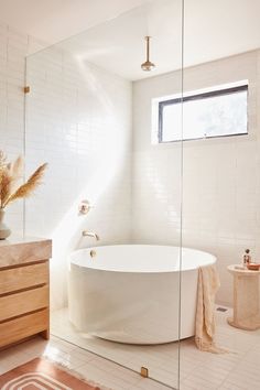 a large white bath tub sitting next to a wooden cabinet in a bathroom under a window