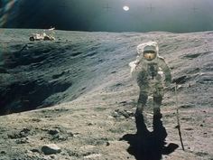 an astronaut walking on the surface of the moon with two astronauts in the distance behind him