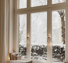 a living room filled with lots of windows covered in snow next to a christmas tree