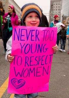 a young boy holding a sign that says never too young to respect women