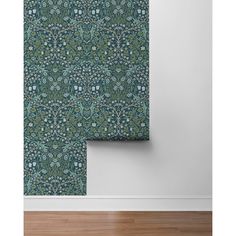 a green wallpaper with blue and white flowers on it, next to a wooden floor