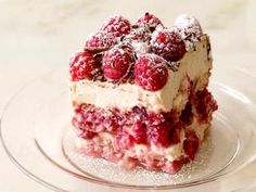 a piece of cake with raspberries on top is sitting on a glass plate