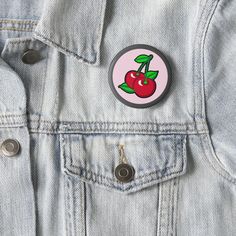 a button with a cherry on it sitting in the pocket of a jean jacket,