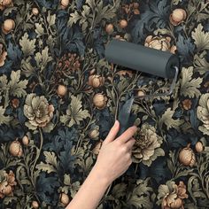 a person using a paint roller on a floral wallpaper