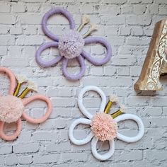 three different colored hair clips hanging on a brick wall