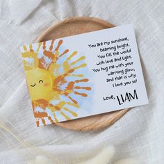 a card with a handprinted sun on it sitting on top of a wooden plate