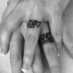 two people with tattoos on their fingers holding each other's hands and one has the word