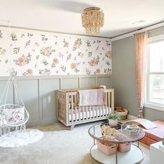 a baby's room with floral wallpaper and furniture