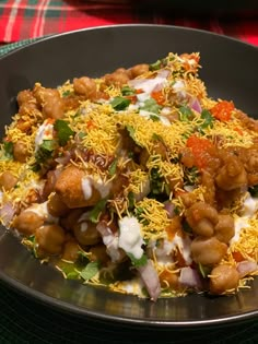 a black plate topped with lots of food on top of a green tablecloth covered table