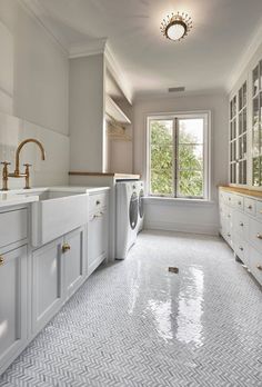 a washer and dryer in a large white kitchen with gold handles on the doors