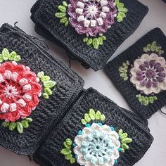 four crocheted coasters with flowers on them sitting next to each other in front of a white wall