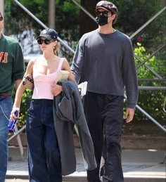 two men and a woman walking down the street with masks on their faces as they walk