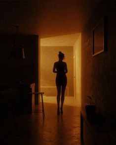 a woman walking down a hallway in the dark with her back turned to the camera