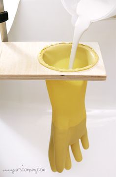 a pair of yellow rubber gloves sitting on top of a wooden table under a white umbrella