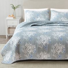 a bed covered in blue and white bedspread with sea corals on it