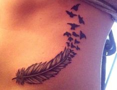 a woman's stomach with a feather and birds flying around her tattoo on it