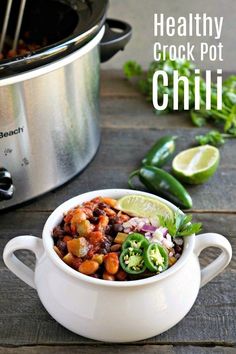 healthy crock pot chili in a white bowl with limes and cilantro