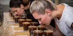 two women sitting at a long table with cups of chocolate pudding in front of them