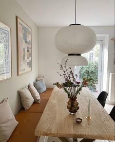 a wooden table topped with vases filled with flowers sitting next to a wall mounted art piece