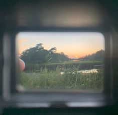 the reflection of trees and water in a small square window with a blurry background