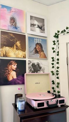 a pink record player sitting on top of a wooden table next to pictures and a plant