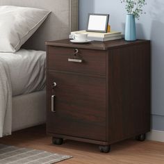 a night stand with two drawers and a bed in the background on a hardwood floor