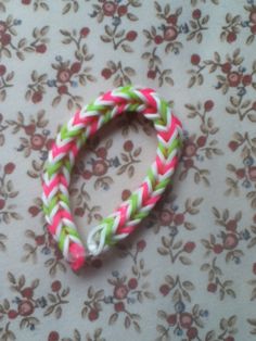 a pink and green bracelet sitting on top of a flowered tablecloth covered floor