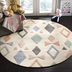 two teddy bears are sitting on the floor in front of a rug with geometric shapes