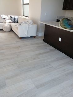 a living room with white furniture and wood flooring